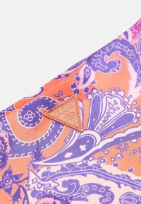 Silkkihuivi, jossa on oranssi ja violetti paisley-kuvio. Kolmion muotoinen logo-tarra beige-värisenä reunassa, joka tuo esiin merkittävän yksityiskohdan.