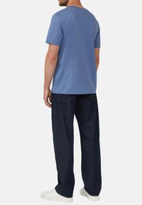 Lichtblauw T-shirt met korte mouwen en ronde hals, gecombineerd met donkerblauwe losse broek en witte sneakers. Eenvoudig ontwerp, geen patronen.