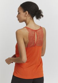 Orange tanktop med en blonde ryg og en nøglehulldetalje. Blødt stof og ærmeløs design giver et afslappet look.
