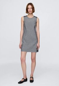 Rochie fără mâneci în carouri alb-negru, cu o siluetă ajustată, cu accente pe umeri și confecționată dintr-un material neted.