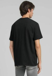 T-shirt di cotone nero con vestibilità comoda, scollo rotondo e maniche corte. Tessuto liscio senza motivi o dettagli visibili.