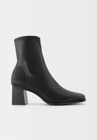 Czarny botek na kostkę wykonany z gładkiego materiału syntetycznego, z ostrym czubkiem i słupkowym obcasem o teksturowanym wzorze.