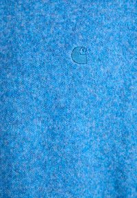 Tissu en polaire bleu présentant une texture subtile, avec un logo brodé de la même couleur. Apparence douce et chaude, teinte uniforme.