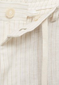 Beige and cream striped fabric with two buttons, a drawstring, and a soft, textured finish, suitable for lightweight garments.