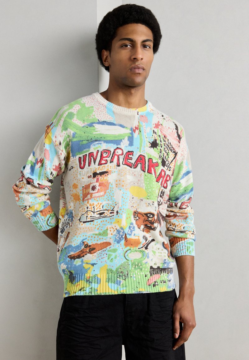 Πλεκτό πουλόβερ με πολύχρωμο αφηρημένο σχέδιο και τη λέξη "UNBREAKABLE" με κόκκινα γράμματα, στρογγυλή λαιμόκοψη και ριμπ μανσέτες.