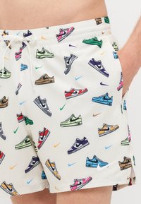 Fehér úszóshort, amelynek több színben pompázó sneaker mintázata van, zöld, kék, lila és piros különböző formákban. Rugalmas derékrész.