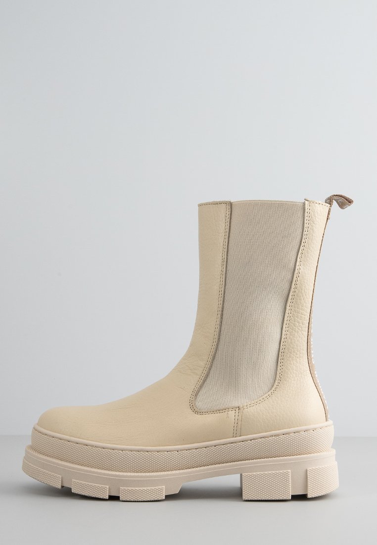 Stivaletto beige con tomaia in pelle liscia e pannelli laterali elasticizzati. Presenta una suola spessa e testurizzata con design a tasselli e un'apposita linguetta per il sollevamento.