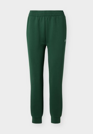 Pantaloni sportî verde închis cu talie elastică și manșete la gleznă, având un mic logo alb pe coapsa dreaptă.