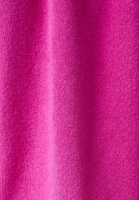 Tissu texturé rose vif avec des boucles tissées visibles, créant des plis verticaux doux et des ombres.