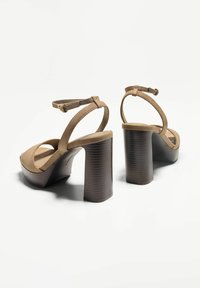 Brown suede high-heeled sandals with ankle straps, open toe, and a ridged block heel. The platform adds extra height for comfort.