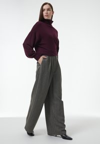 Bordeaux turtleneck trui met een relaxte pasvorm; gecombineerd met hoogwaardige, wijdvallende grijze broeken met een subtiel patroon en zijzakken.