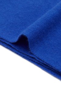 Tessuto di lana blu con una finitura morbida e testurizzata, piegato per mostrare profondità e colore ricco. Accentuato da una leggera peluria.