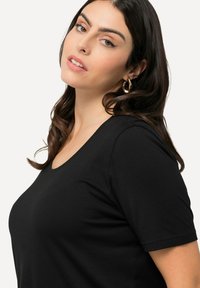 T-shirt nero a maniche corte con scollatura a barca, realizzato in tessuto morbido, con una texture liscia e un fit rilassato.