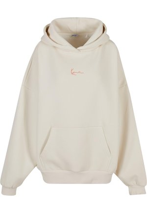 Beige oversized hoodie i mjukt tyg, med en känguruficka och en broderad logotyp i korall på bröstet. Klassisk design med ribbade muddar.
