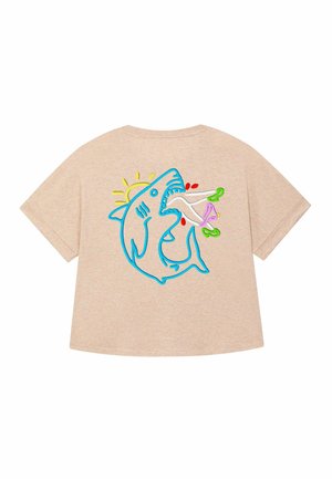T-shirt beige con vestibilità ampia. Presenta uno squalo blu ricamato con un sole, che tiene in mano oggetti colorati. Maniche corte e texture morbida.