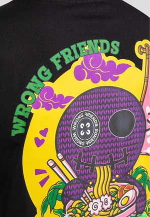 Camiseta negra con un diseño gráfico vibrante en amarillo y púrpura que incluye el texto "AMIGOS EQUIVOCADOS" y un esqueleto de dibujos animados rodeado de elementos de comida.