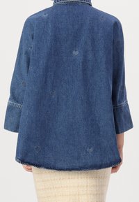 Giacca di jeans blu scuro con una vestibilità ampia, caratterizzata da ritagli a forma di cuore, maniche a tre quarti e orlo arrotondato.
