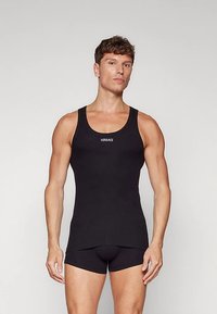 Svart linne i stretchigt tyg med rund halsringning och smal passform. "Versace"-logotyp i vitt tryckt på framsidan.