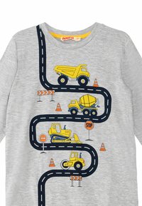 Harmaa paita, jossa on sarjakuvamaineinen tiekuvio, jossa on keltaisia rakennusautoja, liikenteen neuleita ja kylttejä leikkimielisessä asettelussa.