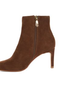 Bottine en suede marron avec un embout pointu, détail de fermeture éclair dorée et un talon fin. Elle présente une texture lisse et une silhouette élégante.