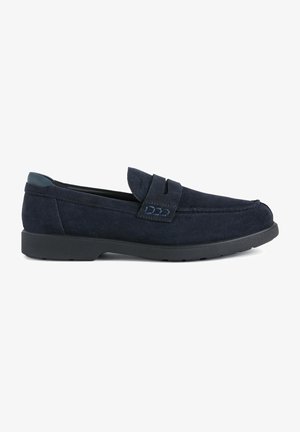Mocassin en suede bleu marine avec un bout arrondi et un design à enfiler. Présente une lanière texturée et une semelle en caoutchouc noir pour une meilleure adhérence.