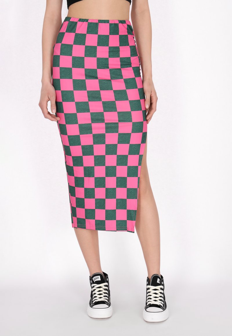 Közepes hosszúságú szoknya rózsaszín és zöld kockás mintával. Oldalsó hasítékkal és gumírozott derékkal rendelkezik. Fekete, magas szárú sportcipővel párosítva.