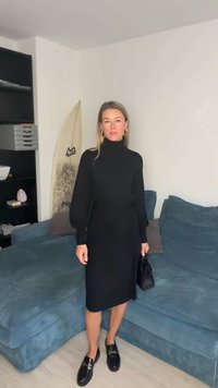 Melna, garām piedurknēm kleita ar augstu apkakli un piegulošu siluetu. Valkāta ar melnām loaferiem un turot nelielu melnu rokassomu.
