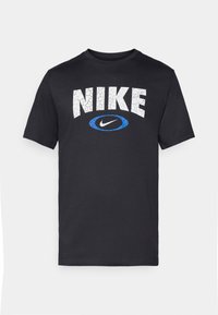 Crna pamučna majica s velikim, napuklim bijelim natpisom "NIKE" i plavim ovalnim_Logom ispod. Klasičan okrugli izrez i kratki rukavi.