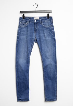 Blaue Jeans aus Denim mit verwaschenem Look, vorderer Knopfleiste und Reißverschluss, Gürtelschlaufen und fünf Taschen, aufgehängt an einem schwarzen Clip-Bügel.