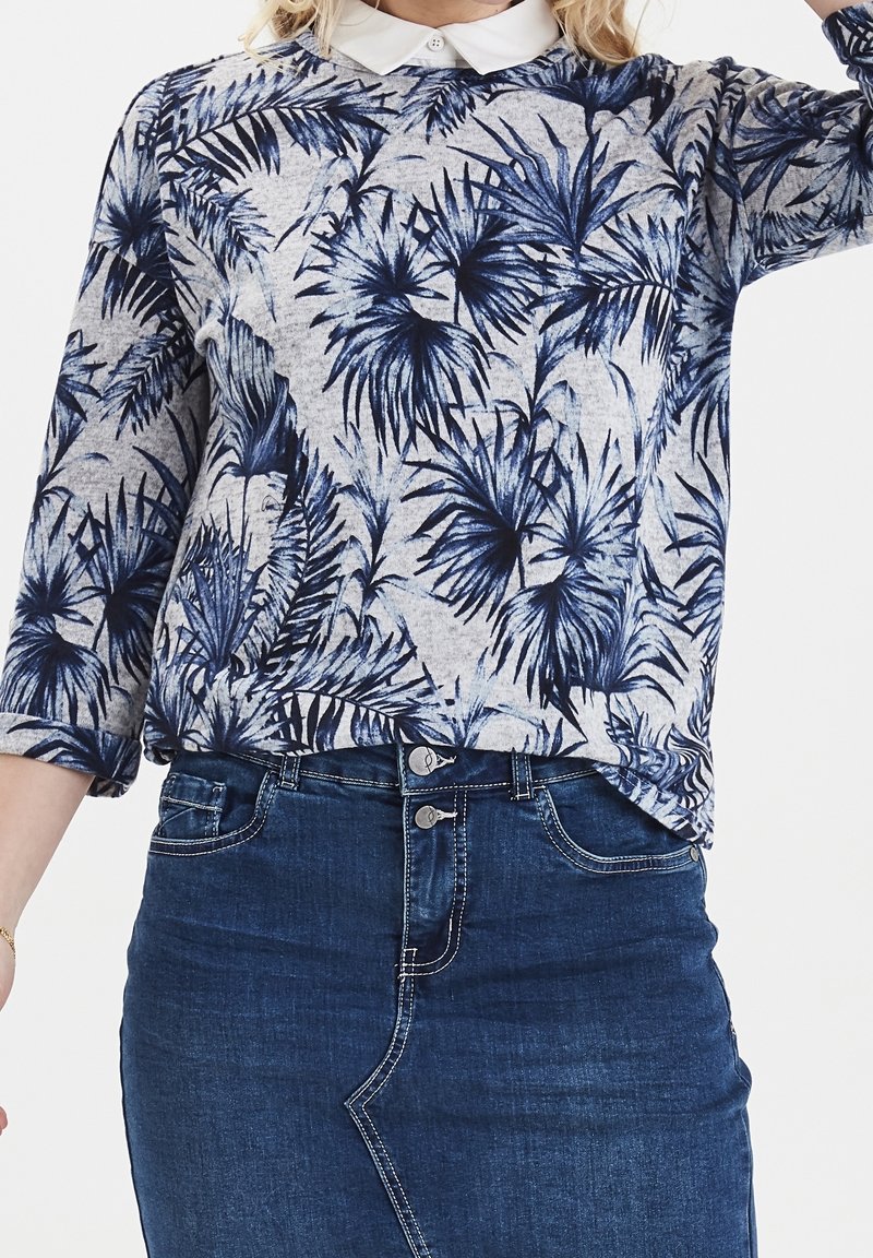 Blauw en grijs langemouwenshirt met palmbladmotief, gemaakt van lichtgewicht materiaal, gecombineerd met een donkere denimrok met een sluiting met twee knoppen.