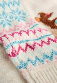 Strickpullover mit einer cremefarbenen Basis, verziert mit pastellrosa und blauen Zickzack- und Schneeflockenmuster, feine Textur mit leichtem Glanz.