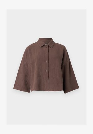 Barna, gyűrött textúrájú, gombos ing széles ujjal és klasszikus gallérral, fehér háttér előtt.