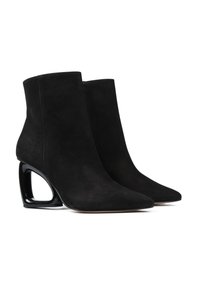 Czarne zamszowe botki za kostkę z ostrymi noskami i unikalnymi hollow block obcasami, pokazane w parze obok siebie na białym tle.