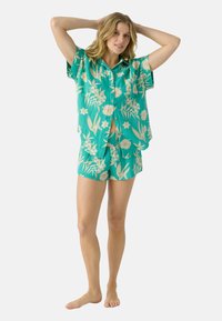 Turkoois bloemen pyjama set met korte mouwen, bestaande uit een knoopsluiting top en bijpassende short, gemaakt van lichte stof met een gestructureerde afwerking.