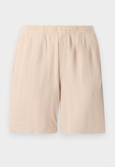 Shorts à taille élastique beige avec un motif discret en chevrons texturés, longueur au genou, présentés sur un fond clair uni.