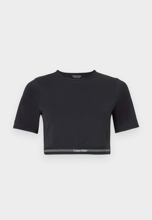 Tricou crop negru cu mâneci scurte, realizat dintr-un material neted. Are o bandă gri la tiv cu logo-ul "Calvin Klein" alb.