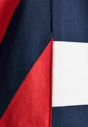 Nahaufnahme von Stoffpaneelen, die in Marineblau, Rot und Weiß zusammengenäht sind und geometrische Formen bilden.