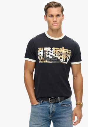 Camiseta negra con cuello y puños en crema, que presenta un estampado gráfico multicolor con el texto "superdry" en un estilo estilizado.