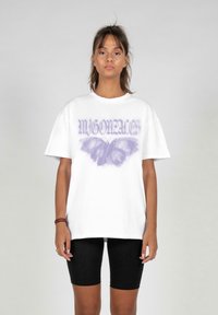 Hvid bomulds t-shirt med et lilla sommerfugl grafik og teksten "MY GONZALES". Korte ærmer og afslappet pasform. Bæret med sorte shorts.