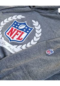 Grauer Hoodie mit einem großen weißen Lorbeerkranz und NFL-Logo in Rot und Blau. Kleines NFL-Logo als Akzent am Ärmel. Weicher, strukturierter Stoff.