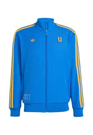Veste de survêtement bleue en tissu lisse, avec des rayures jaunes sur les épaules, fermeture éclair frontale, col montant et logos brodés sur la poitrine et la poche.