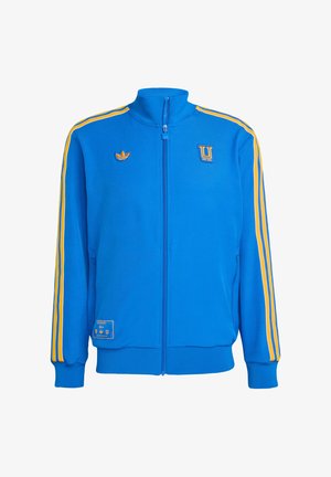Blue track jacket made of smooth fabric, featuring yellow shoulder stripes, zippered front, high collar, and embroidered logos on chest and pocket.