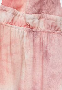 Tela de teñido anudado en rosa y blanco con costura elástica fruncida que crea una textura de volantes.