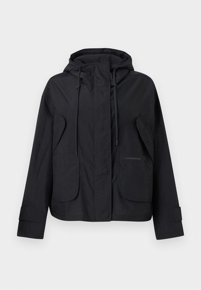 Veste noire à capuche avec poches à rabat à l'avant, cordons de serrage ajustables sur la capuche et bandes auto-agrippantes aux poignets.