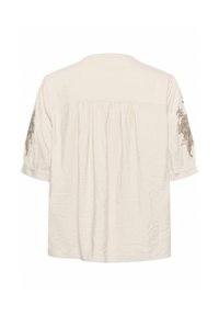 Blouse à manches courtes couleur crème avec un dos froncé et des broderies florales sur les manches, fabriquée en tissu léger et froissé.