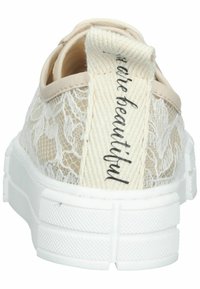 Baskets en dentelle beige avec une semelle en caoutchouc blanche et un talon texturé. Présentent une boucle arrière en tissu tissé avec le texte « you’re beautiful ».