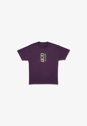 T-shirt en coton violet avec un design graphique central comportant des motifs circulaires et des accents marquants. Manches courtes et col rond.