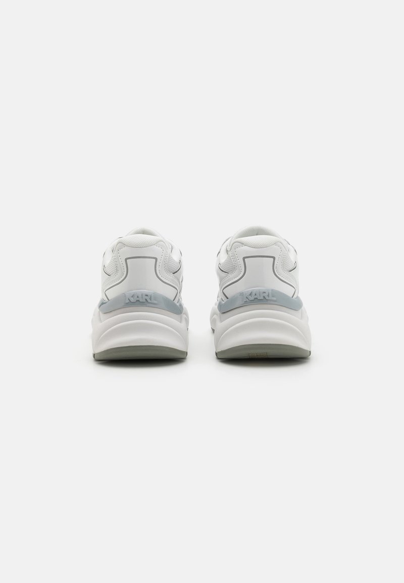 Baskets blanches avec une tige en cuir lisse, un col rembourré et un détail de logo sur le talon. Semelle en caoutchouc avec une finition texturée.