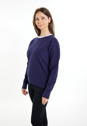 Pulover tricotat mov cu decolteu rotund și manșete cu nervuri, purtat peste pantaloni negri. Materialul pare moale, cu o textură netedă.