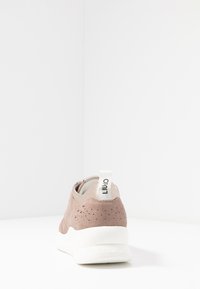 Różowe zamszowe sneakersy z perforowaną teksturą, beżowym syntetycznym akcentem na pięcie i białą gumową podeszwą. Posiadają oznakowaną pętelkę do zakładania.